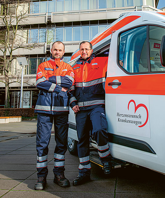 Zwei Malteser-Mitarbeiter an einem Krankenwagen (Foto)